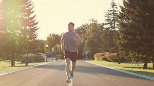 Male runner training to run marathon in park at sunset. Sport man exercise outdoor. Young man training in summer park