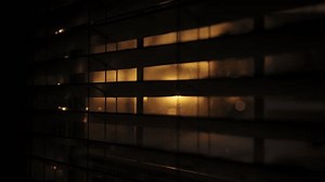 Looking at golden sunset through window closed by blinds. Close up footage