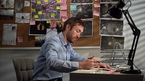Private Detective working with evidence at desk in office