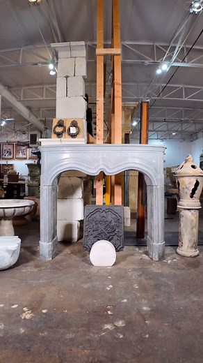 MANTEL—Carved in the 19th century from Belgian bluestone, this mantel carries a graceful serpentine arch framed by classic fluted legs, giving it a balanced and architectural presence. At the center, a circular carved motif adds a refined focal point, its detailing catching the light in subtle ways. The surface shows a soft patina and gentle wear from over a century of use, bringing a depth and authenticity that makes this piece feel both timeless and inviting. (SKU: M-G3E5) available for purcha
