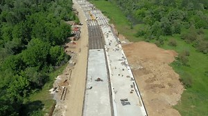 Highway bridge under construction. Infrastructure at a motorway road construction site. Freeway being built on a mountain terrain. Aerial view of new highway construction site with overpass section
