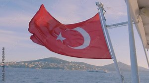 Beautiful sunny view of Turkey flag waving in the wind on a boat cruising at summer sea and city background