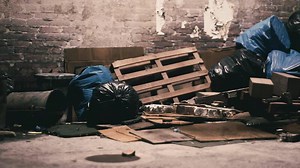 Debris and waste piled in an abandoned urban alleyway during daylight hours