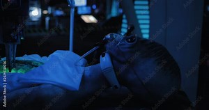 Alien lies in the operational unit of the space laboratory. Sensors are connected, the opening of humanoid using equipment.