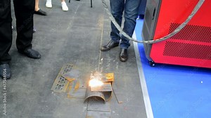 Laser cleaning of metal. Industrial laser cleaning rust of metal. Industrial removal of rust of metal surface with laser beam. Man cleaning surface from corrosion with laser metal cleaning machine