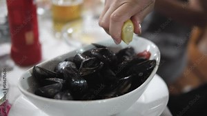 Woman putting lemon juice on the freshly cooked mussels in the decorated plate in a resturant Stock Video