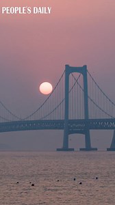 A glowing sun rises over the Xinghai Bay Cross-Sea Bridge in Dalian, northeast China’s Liaoning Province, presenting a breathtaking yet calming scenery. | VideoChina