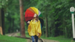 Jolie fille dans un imperméable jaune se promenant sous la pluie avec un parapluie | Vidéo de stock Gratuit