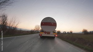 Rear view of white cistern truck driving fast on highway at sunset