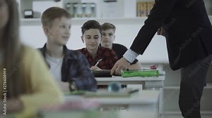 Male teacher handing out laptops to his students to teach programming and computer science at a school.