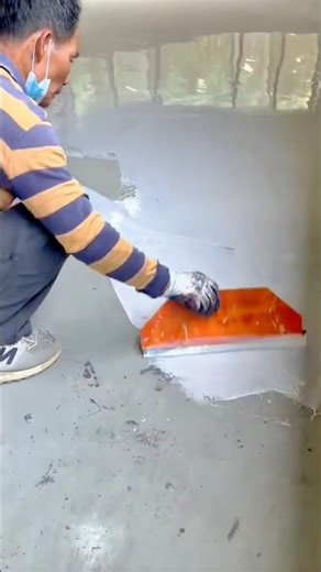 Applying self-leveling epoxy coating evenly across the concrete floor surface