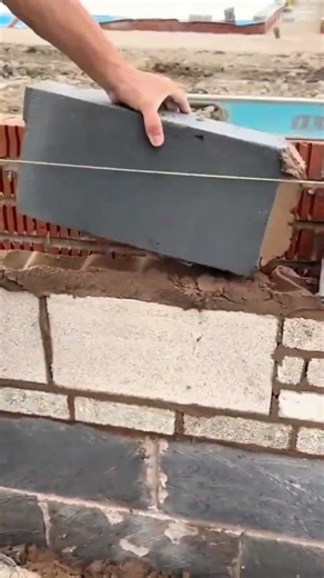 applying mortar paste onto concrete blocks to build a sturdy wall during a house construction proces