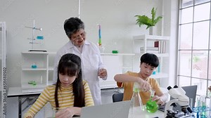 senior science teacher Introducing school girls and boys Cute Asian people experiment with mixing colors in test tubes in science in the classroom. Learn about experiments in the school lab