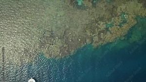 Aerial flat laid perspective of a yacht near a coral reef in the Red Sea, with tourists in one boat near Jeddah in Saudi Arabia. Blue, green and turquoise waters