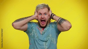 Bearded adult guy scared fearful, covering ears with hands, closing eyes, meeting his own phobia, evidence horror event, screaming, shouting at loud, freaked out. Young cute man on yellow background