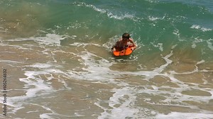 Two young boys boogie boarding in ocean, slow motion