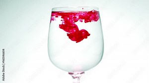Red ink drops into the water and slowly spreading red throughout the area to fill the space