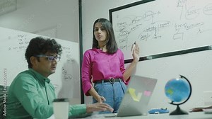 Young indian businesswoman corporate leader coach speaker give flip chart workshop presentation explaining strategy teaching multiethnic staff consult diverse team at office meeting training concept.