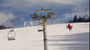 Double chair chairlift (ski lift) tower with sheaves, ropes and carriers on a slope in snow season. Wheels and cables of uphill transportation system for skiers at a mountain winter ski resort.