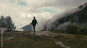 Woman backpacker is standing on top of mount and admiring nature, wide shot