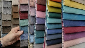 Catalog of textiles for the manufacture of upholstered furniture. Samples of multicolored fabrics. A woman chooses a fabric for a sofa. Color selection. textile industry.