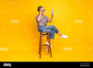 Full size photo of pretty retired female video call sit chair dressed stylish leopard print outfit isolated on yellow color background Stock Photo - Alamy