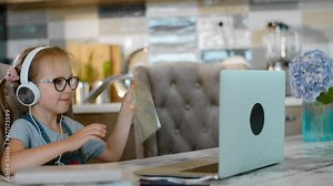 little girl shows homework notebook to online tutor in video call Rbbro. pupil wear headphones during distant learning and talk. concept e-learning, teacher, education. elementary student