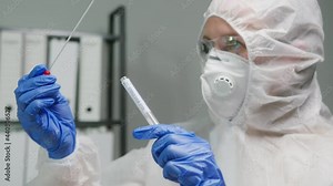 PCR test in laboratory, doctor holding COVID-19 Coronavirus swab collection kit, wearing PPE protective suit mask gloves, test tube for taking OP NP patient specimen sample, writing the results