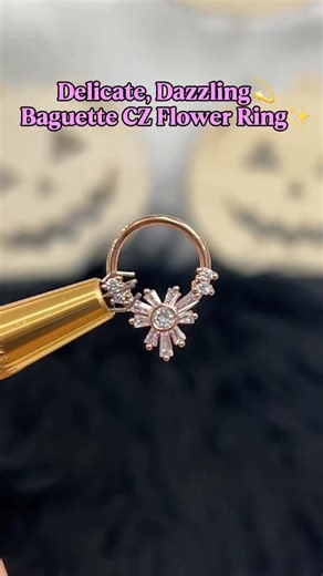 This stunning ring features delicate baguette-cut cubic zirconia petals, designed to sparkle beautifully with every move. Whether you wear it in your nose, cartilage, septum, or lobe, it adds a soft, radiant glow that instantly elevates your look. What makes it special? It’s not just pretty — it’s practical. The hinged segment closure makes it super easy to open, secure, and wear all day long. No irritation, no hassle — just effortless shine and comfort. Perfect for everyday wear or when you wan