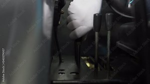 A man, operator, driver in white gloves controls the levers of the attachment of the hydraulic system of a small agricultural tractor. Harvesting, sowing. Agricultural technology. Collective farms.