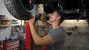 Mechanic working on classic car wheels and suspension in restoration workshop