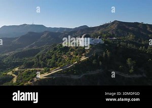 Drone aerial side view of Griffith Observatory surrounded by rugged Hollywood Hills with winding trails, green slopes and bright California daylight Stock Video Footage - Alamy