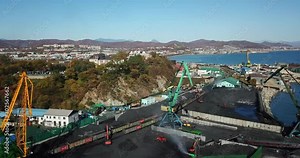 Coal port top view. Loading coal into railway wagons using an excavator. Stevedoring company.