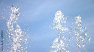 Stream spraying water drops. Drops of up and falling water from the fountain on the blue sky background, natural effect scene, super slow motion, close up. ProRes 422 HQ. Stock Video