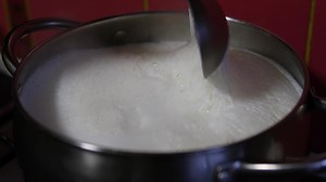 boiling milk with foam Milk boils and steams hot. Boiling milk in stainless steel vessel. milk is about to boil. Boiling milk flows from the pan onto the gas stove. Cow's milked boils in a kettle. 4K