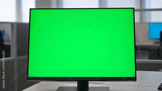 Slow push in close up of computer monitor with green screen in office cubicle workspace interior