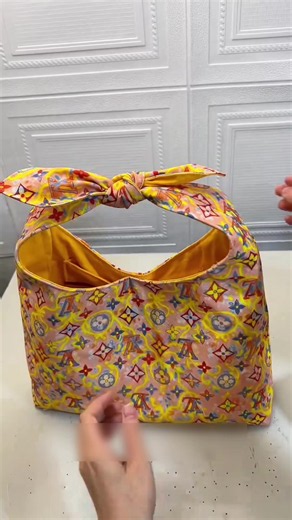 Te enseño a hacer este bolso de mano con moño con un solo molde y medidas sencillas. Corto la base de 44 por 40, le doy la forma de la boca con un bol redondo, armo el fondo con volumen, le pongo forro con bolsillo, botón magnético y lo remato con el moño amarrado al asa. Fácil, bonito y con mucha capacidad. #costura #diy #bolso