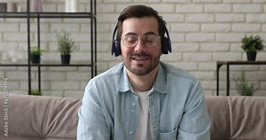Head shot of 35s male applicant pass job interview answer question distantly wear headphones use internet connection computer feels confident. Video call activity, freelance telework from home concept