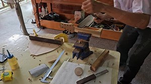 Close up of luthier man's hand filing to removes facets of guitar's neck with file tool at the workshop.