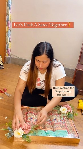 Riwaayat|Wedding Gifts & Packing|Diwali Hampers|Ring Trays 🌸 on Instagram: "⬇️ SAVE THIS REEL for some saree packing inspiration! 🎥✨ 👉🏻Here’s a step-by-step guide to pack a saree in a flat tray: 🌸Arrange and fold the saree to fit the tray, showcasing the border and the intricate work. You can choose to pleat it for an appealing look. 🌸Cut the cellophane sheet slightly larger than the tray’s size, ensuring some extra margin. 🌸Use a hot gun t