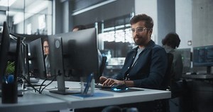 Portrait of a Thoughtful Engineer Working on Desktop Computer in a Technological Office Environment. Research and Development Department Writing Software Code for an Advanced Neural Network Project