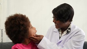 African American dentist examining girls teeth on sofa