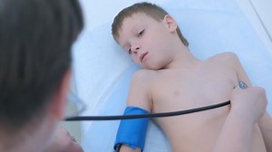 Doctor pediatrician cardiologist listening heartbeat exam of patient child boy using stethoscope on pediatric checkup appointment, children medical healthcare concept. Counting heart beats in minute.