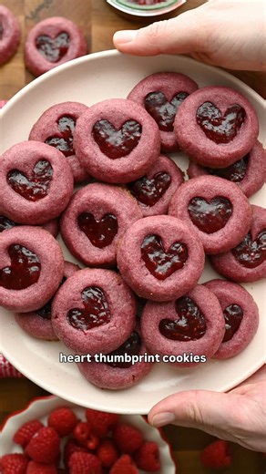 Lexi Harrison & Beth Sinclair on Instagram: "Raspberry Heart Thumbprint Cookies for episode 2 of 💕Love at First Bite!💕 These adorable cookies are packed with tart raspberry flavor, both in the dough (we use freeze dried raspberries) as well as the raspberry jam filling. They’re easy to make, super buttery and genuinely one of my favorite cookie recipes we’ve ever shared! Comment ‘RECIPE’ and we’ll send it to you 💌"