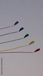 kite show colorful kites fly in the sky in the evening colored kite in the blue sky. Slowed-down shooting of a kite developing against a blue sky and white clouds