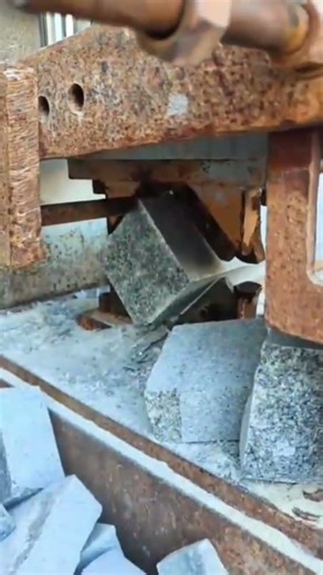 splitting large grey granite blocks into several smaller square bricks using hydraulic press machine