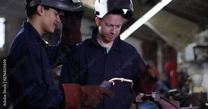4K Experienced welder giving 'on the job' training to young apprentice. Slow motion.