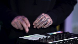 DJ hands with tattooes touch buttons and sliders, playing electronic music. Art. Concept of party, night club and techno music.