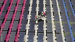 Top and circulate view over two technician workers check the problem of solar cell panel during process of installation and work over water reservoir.