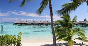 Travel vacation paradise video background with overwater bungalows luxury resort in coral reef lagoon ocean by idyllic beach. 59.94 FPS slow motion. Stock Video